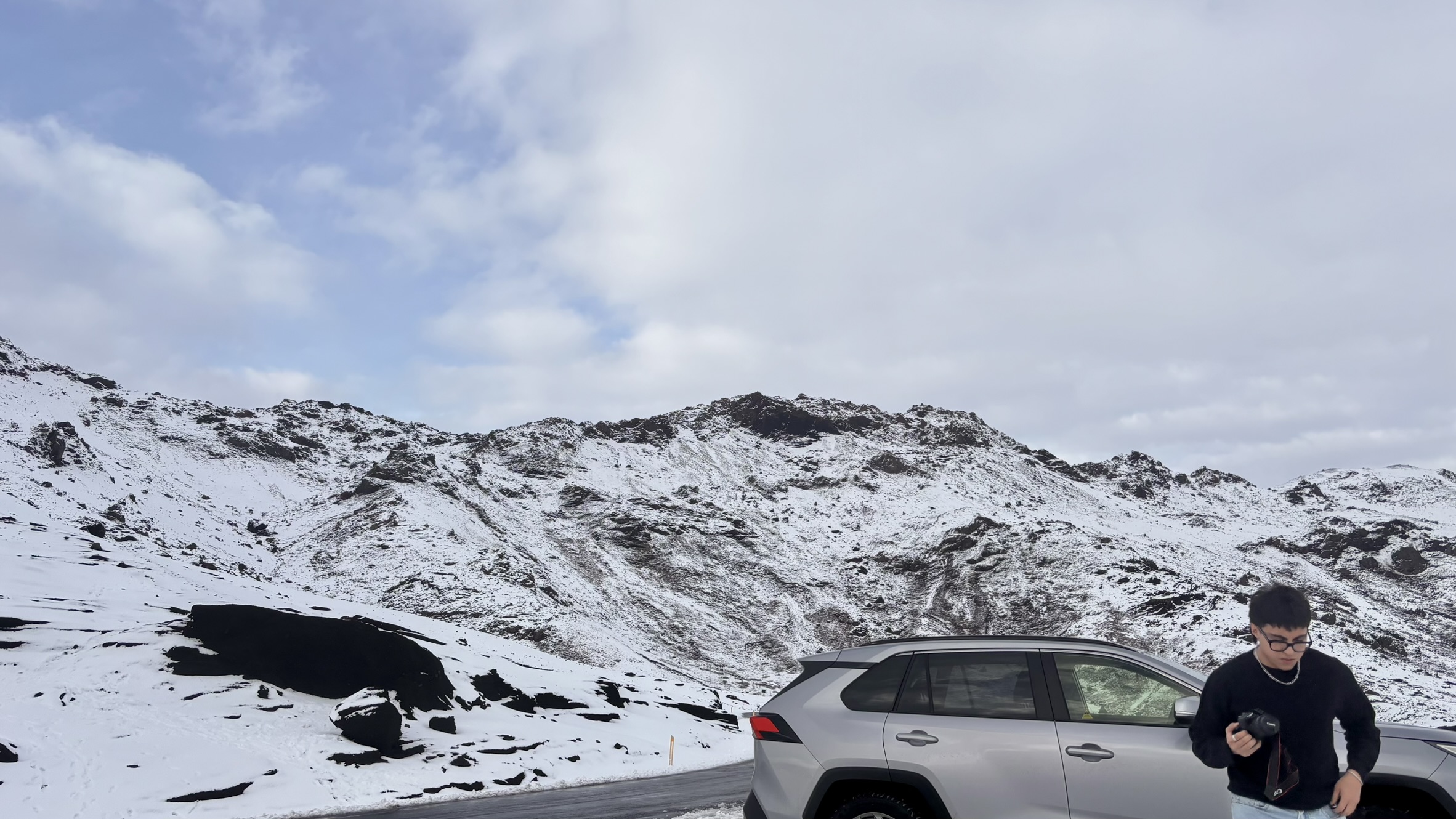 Snowy mountain view with a car and human.